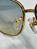 Gold-tone eyeglass lens with clear temple and emblem detail