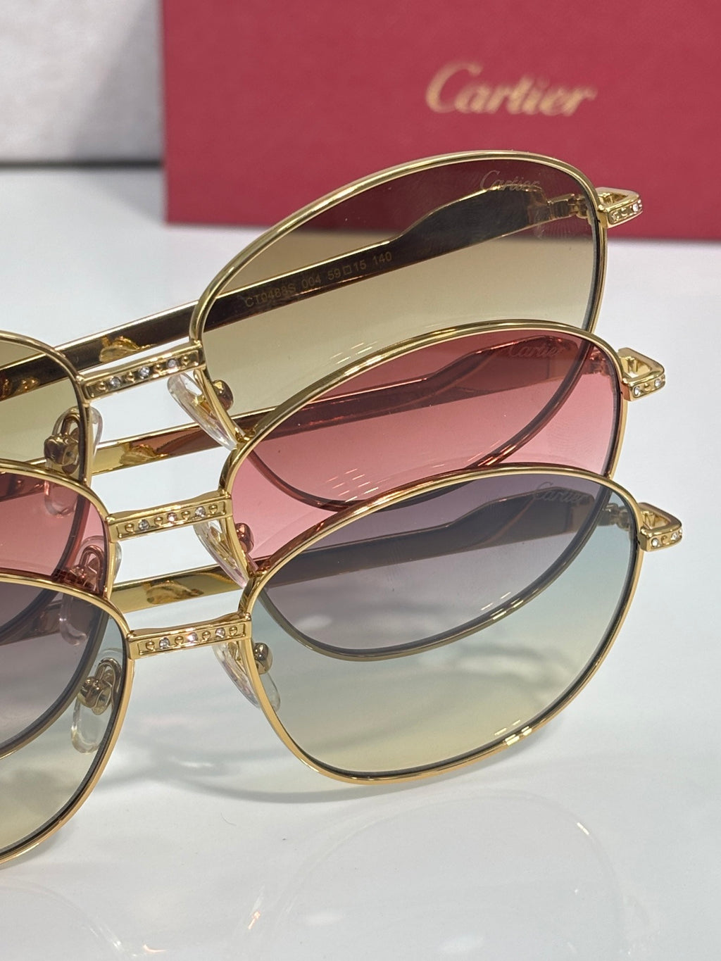 Gold-tone round glasses with pink and blue tinted lenses, stacked