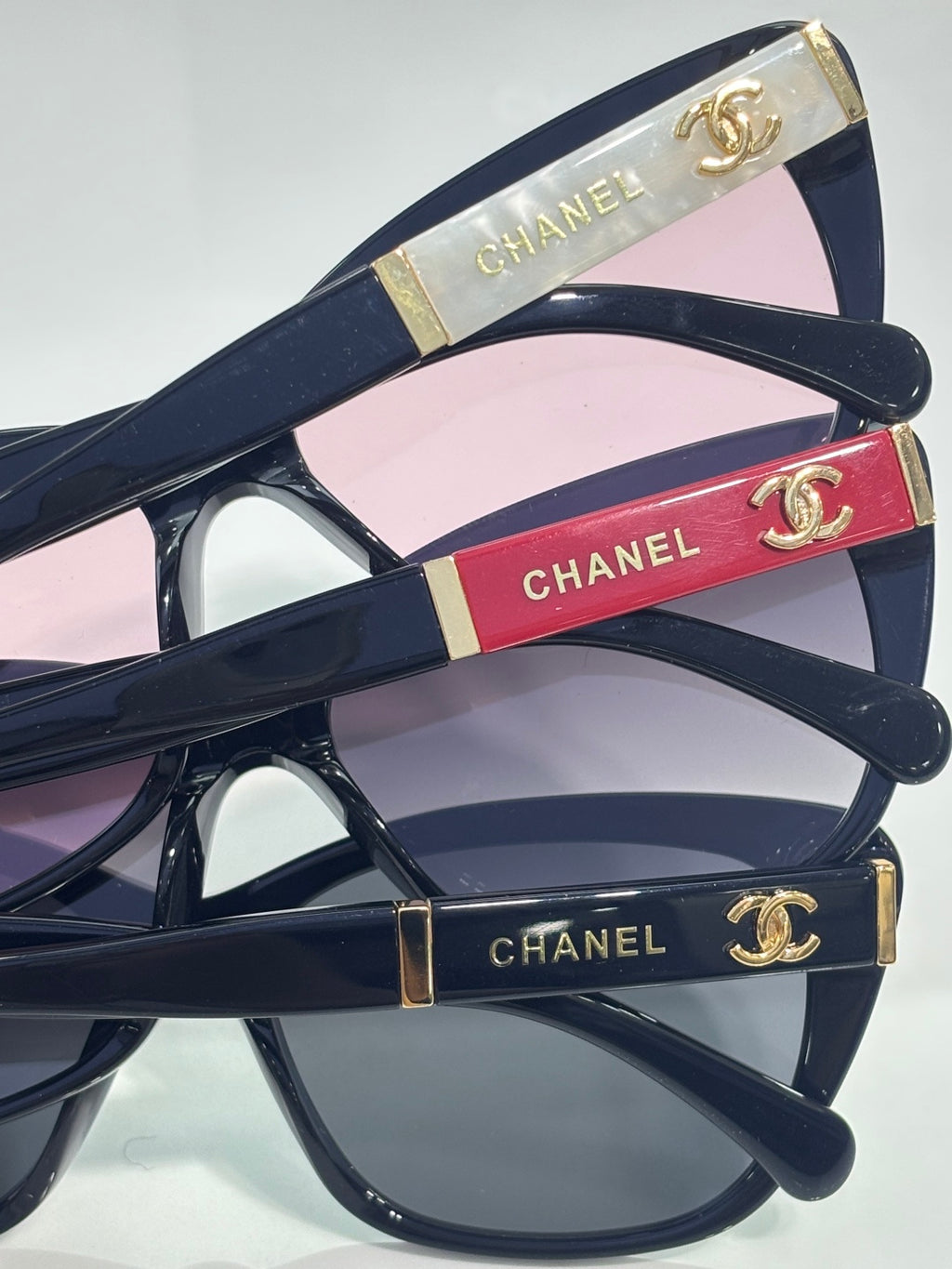 Chanel eyeglasses close-up, navy frames with pink lenses and red enamel stripe