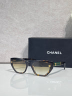 Chanel glasses with dark tortoiseshell frames and beige gradient lenses, gold CC accents