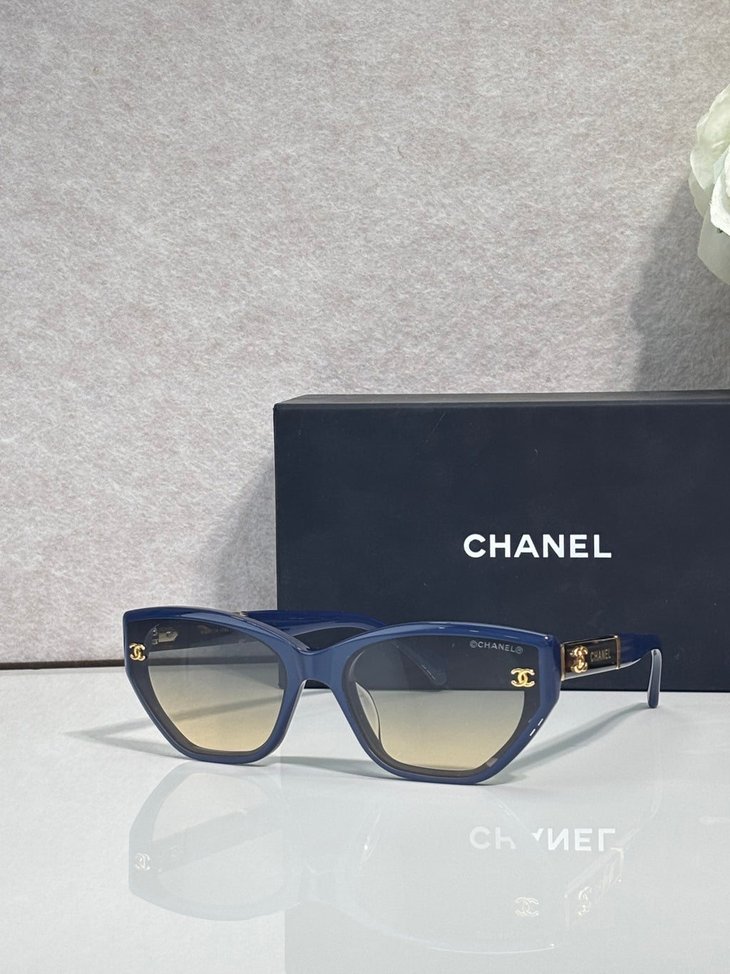 Chanel glasses with navy-blue frames and amber gradient lenses, gold CC details