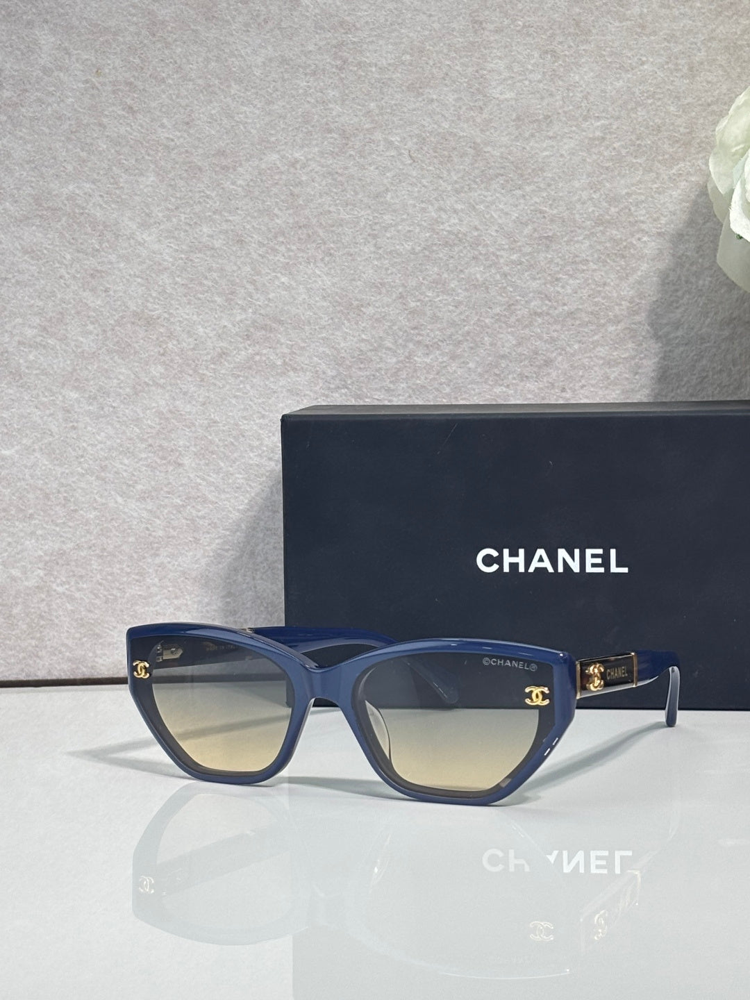 Chanel glasses with navy-blue frames and amber gradient lenses, gold CC details