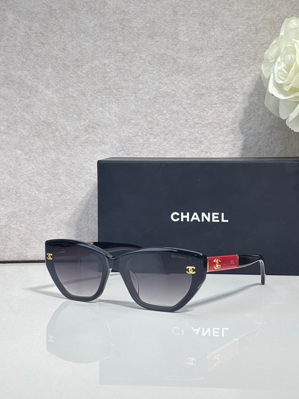 Chanel glasses with dark navy frames and smoky lenses, red temple accent and gold CC