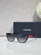 Chanel glasses with dark navy frames and smoky lenses, red temple accent and gold CC