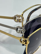 Gold and silver hinge detail with heart-shaped charm on sunglasses frame