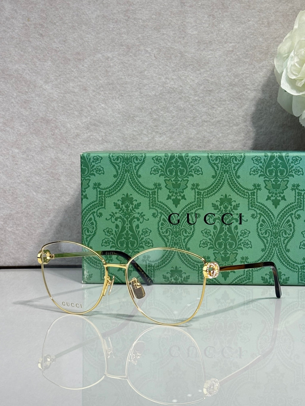 Gold-tone round eyeglasses with clear lenses and green patterned temples