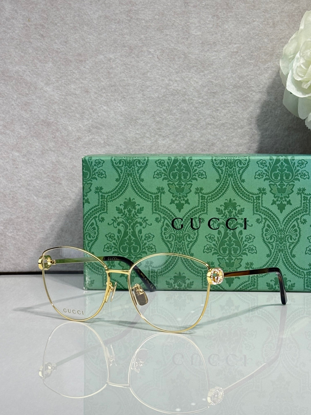 Gold-tone round eyeglasses with clear lenses and green patterned temples