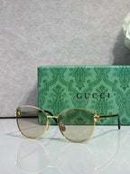 Gold-tone round eyeglasses with clear lenses and green patterned side arms