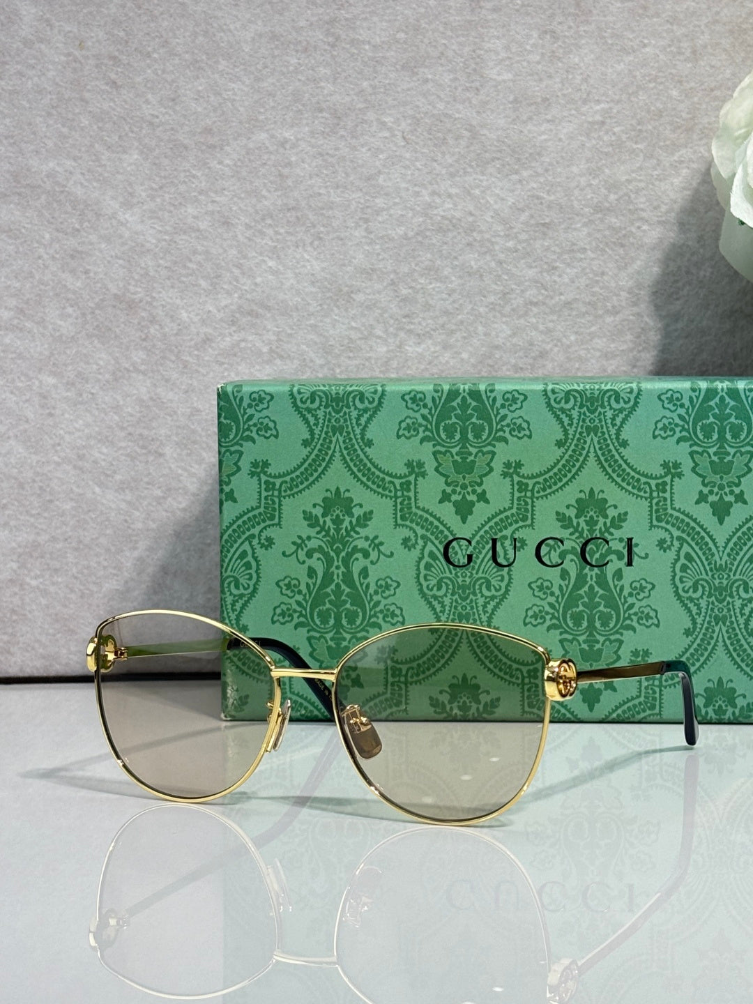 Gold-tone round eyeglasses with clear lenses and green patterned side arms