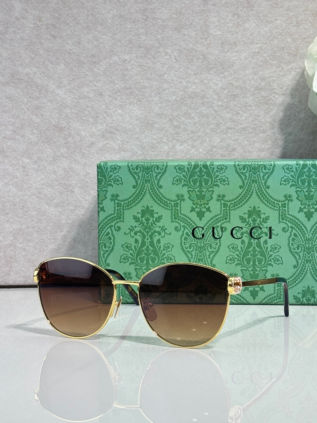 Gold-tone sunglasses with dark lenses and green patterned temples