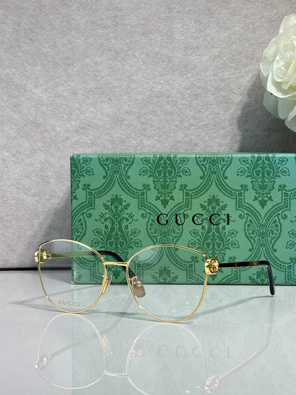 Gold-tone round eyeglasses with clear lenses, green patterned temples and arms