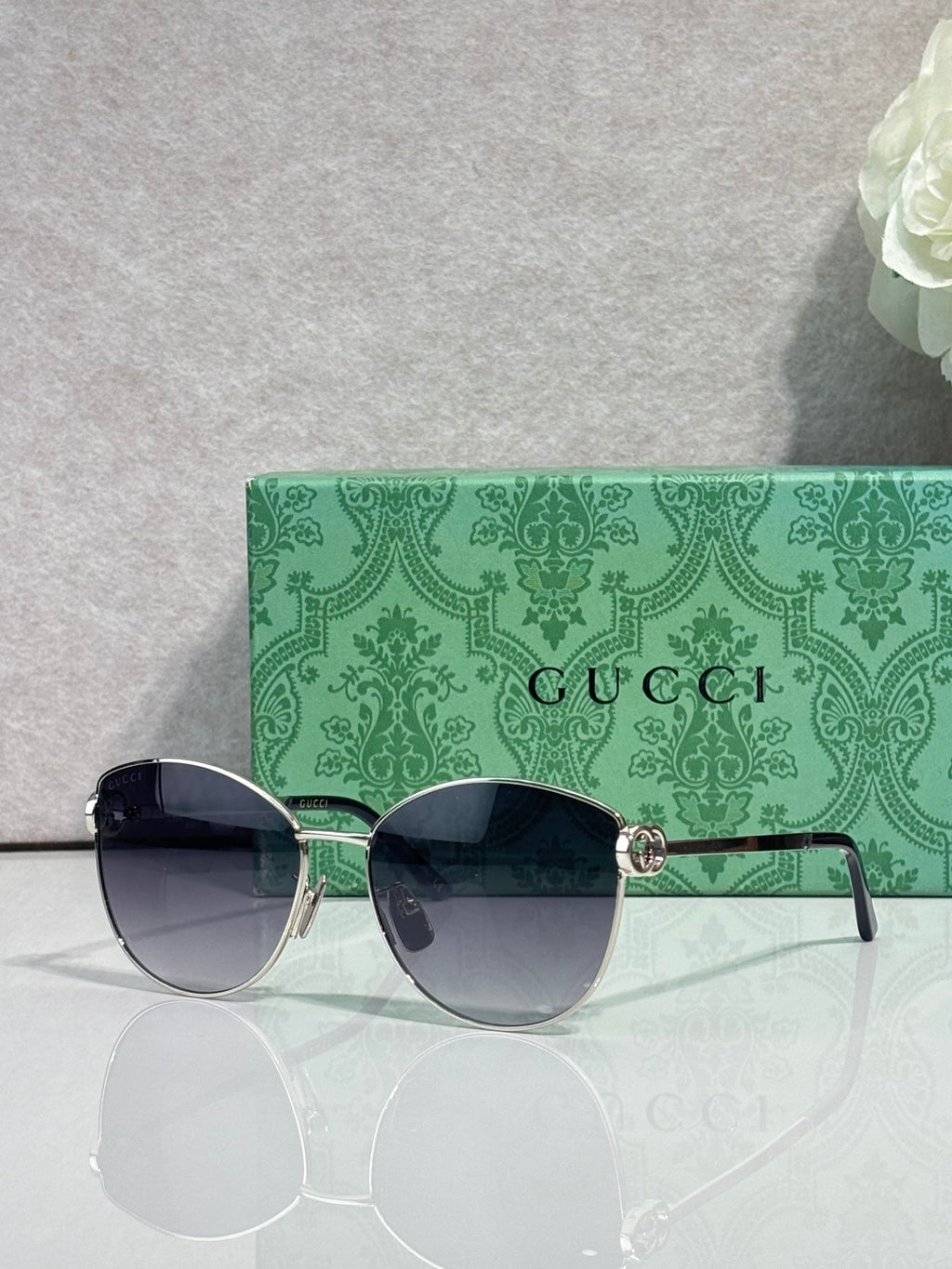 Gold-tone sunglasses with dark lenses and green patterned side arms