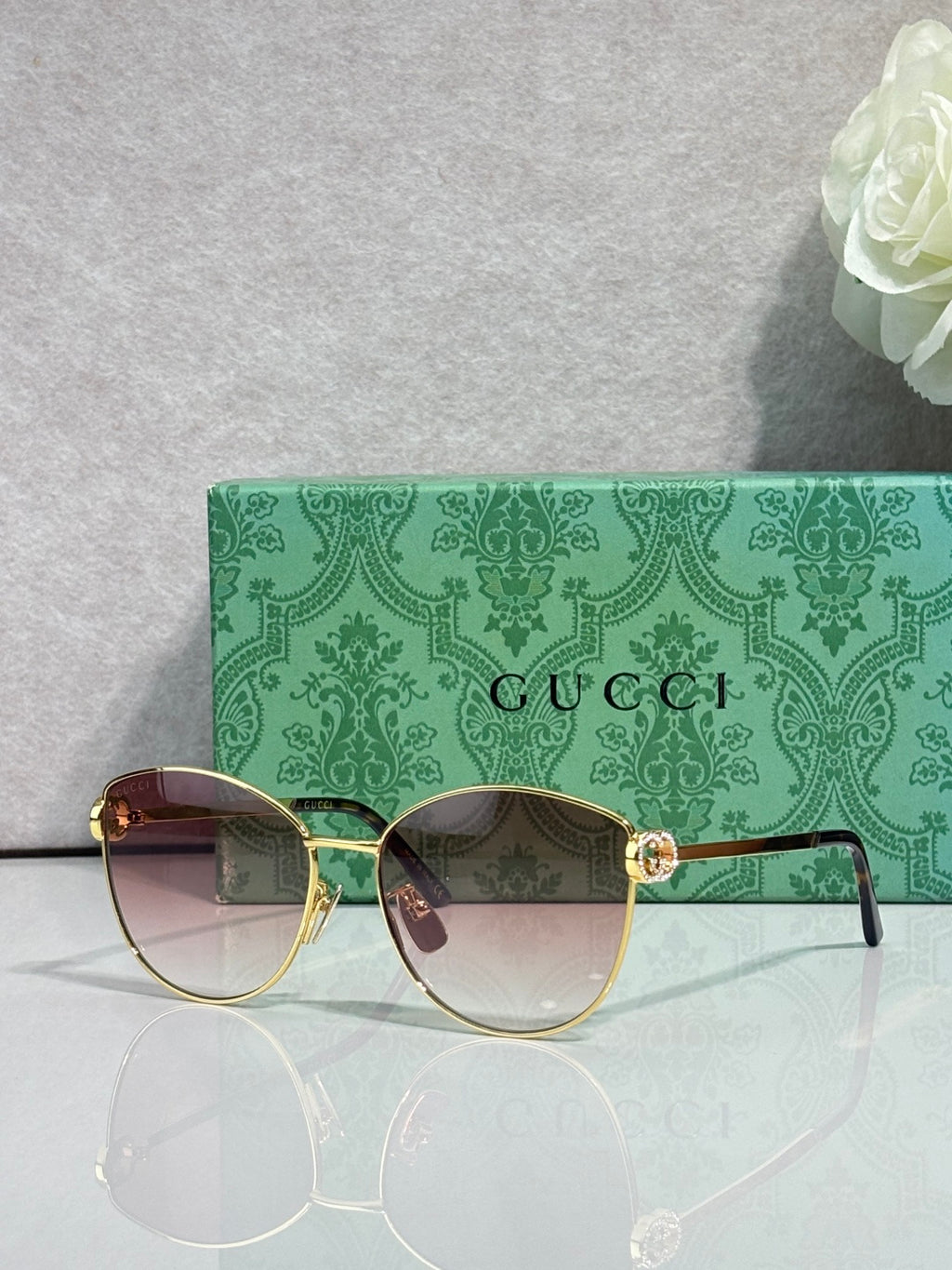 Gold-tone sunglasses with dark gradient lenses and green patterned temples