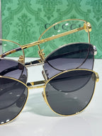 Gold-tone sunglasses with dark lenses and green patterned temples, close view