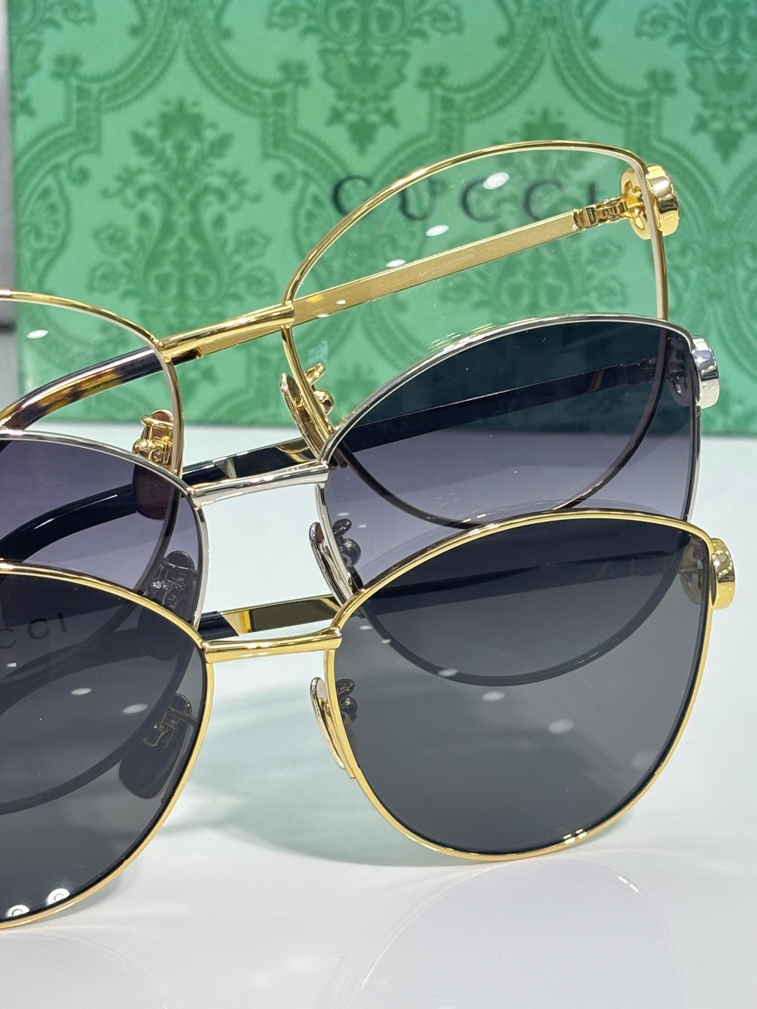 Gold-tone sunglasses with dark lenses and green patterned temples, close view