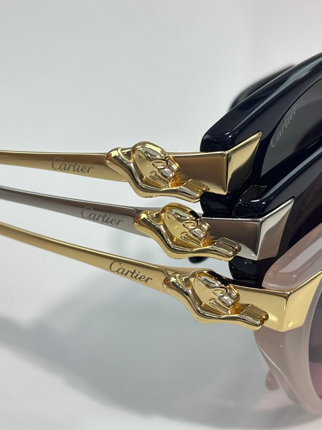 Cartier sunglasses close-up of gold-tone hinge with engraved Cartier logo and dark lens