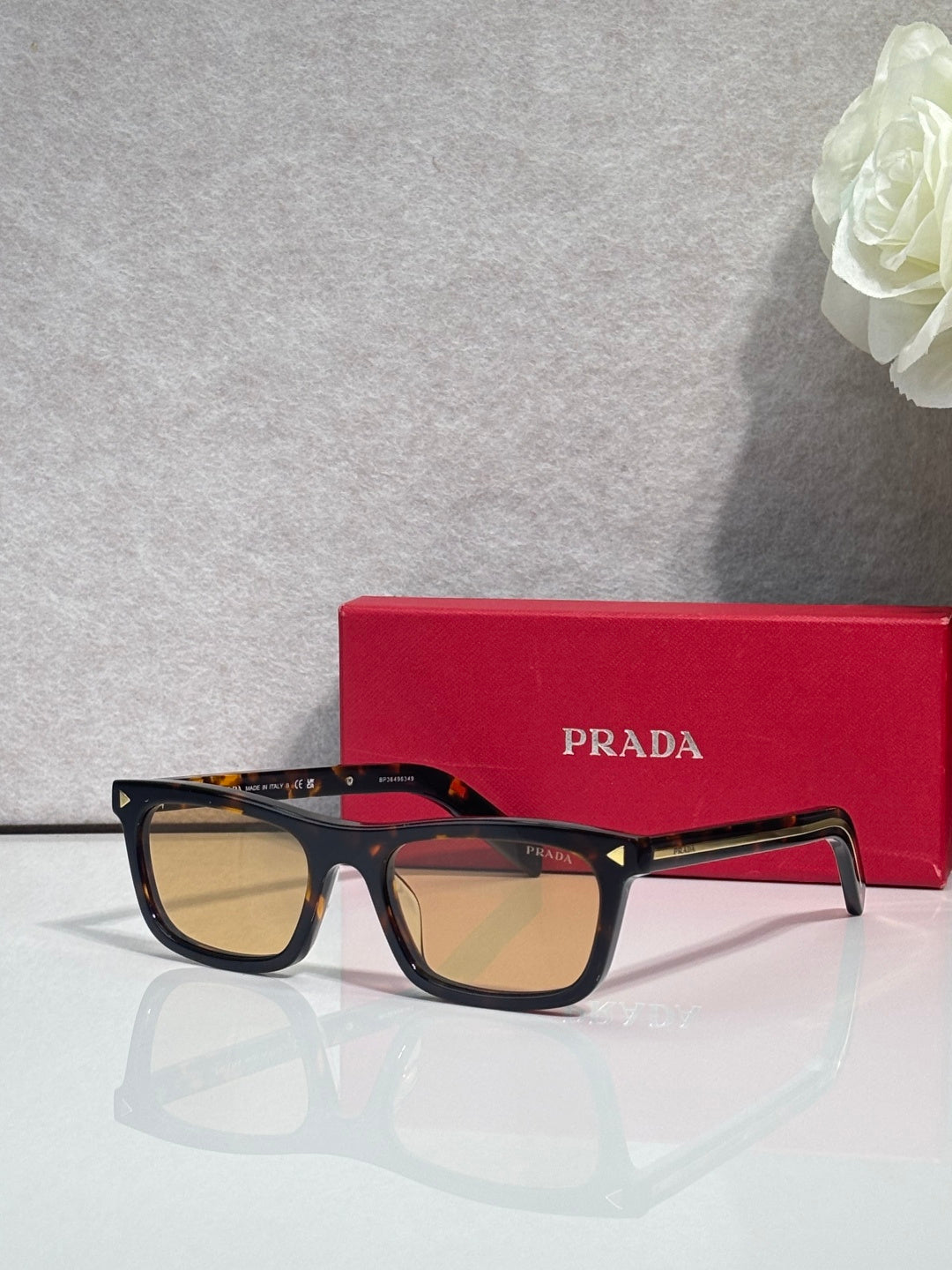Prada eyeglasses with dark frame, tan lenses, and red temple accents