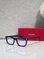 Prada eyeglasses in dark frame with blue-tinted lenses and red temple accents
