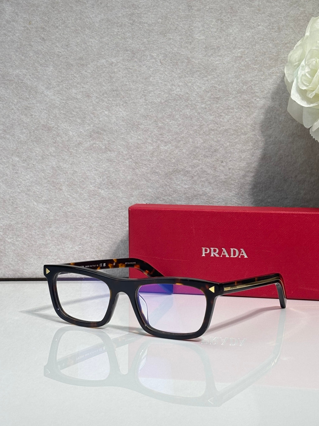 Prada eyeglasses with dark frames and clear lenses, red temple accents