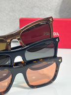 Prada eyeglasses closeup, black frames with brown lenses and gold logo details