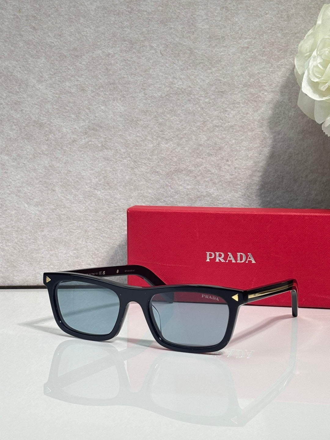Prada eyeglasses with dark frame and translucent blue lenses; red temple accents