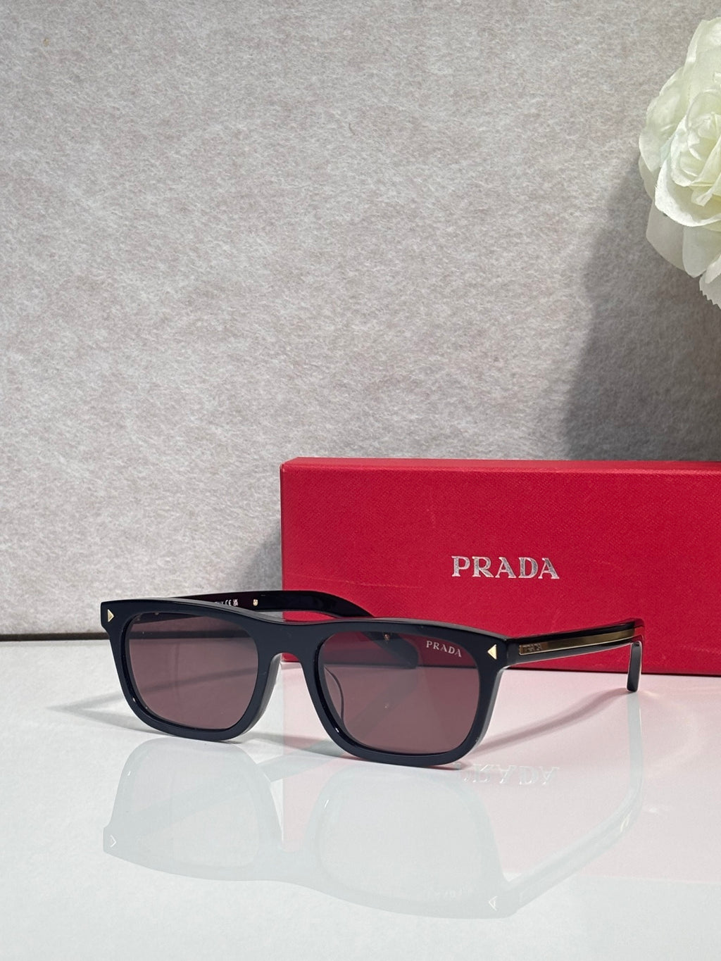 Prada eyeglasses with dark frame, brown lenses, and red temple accents