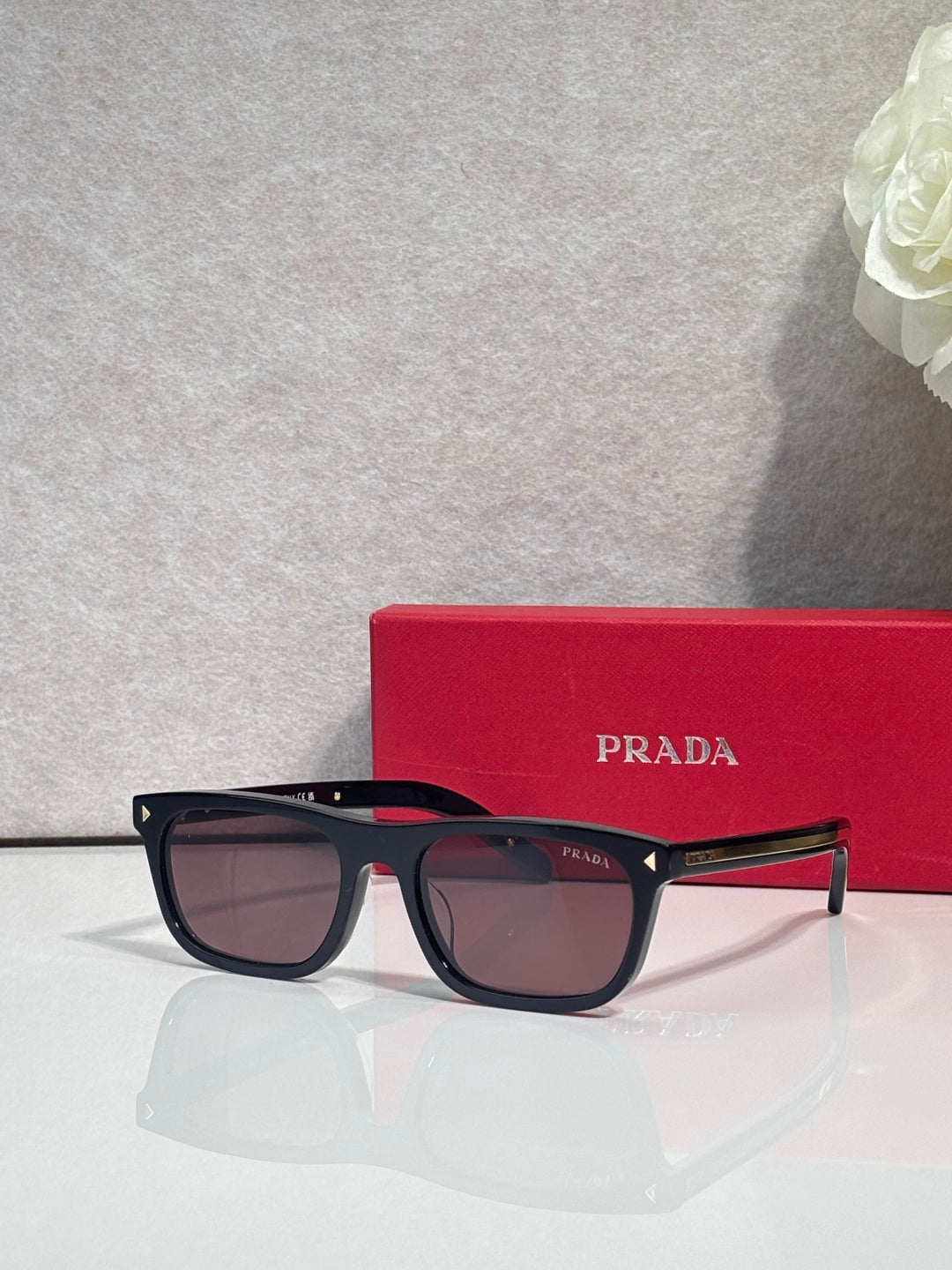 Prada eyeglasses with dark frame, brown lenses, and red temple accents