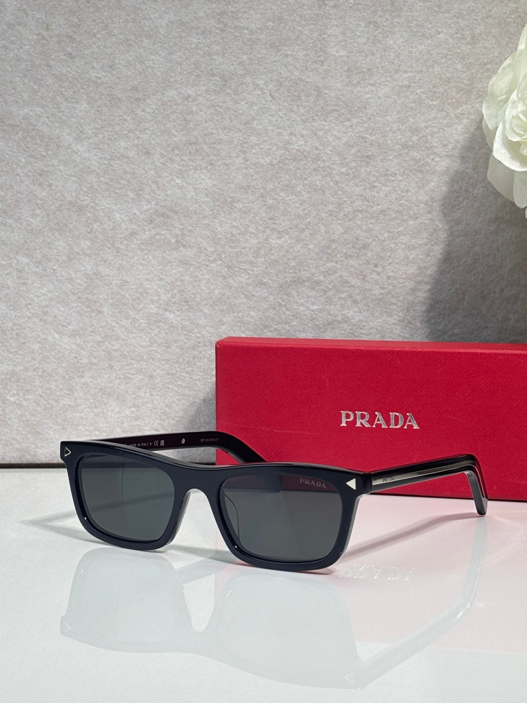 Prada eyeglasses with dark frame and dark lenses; red temple accents