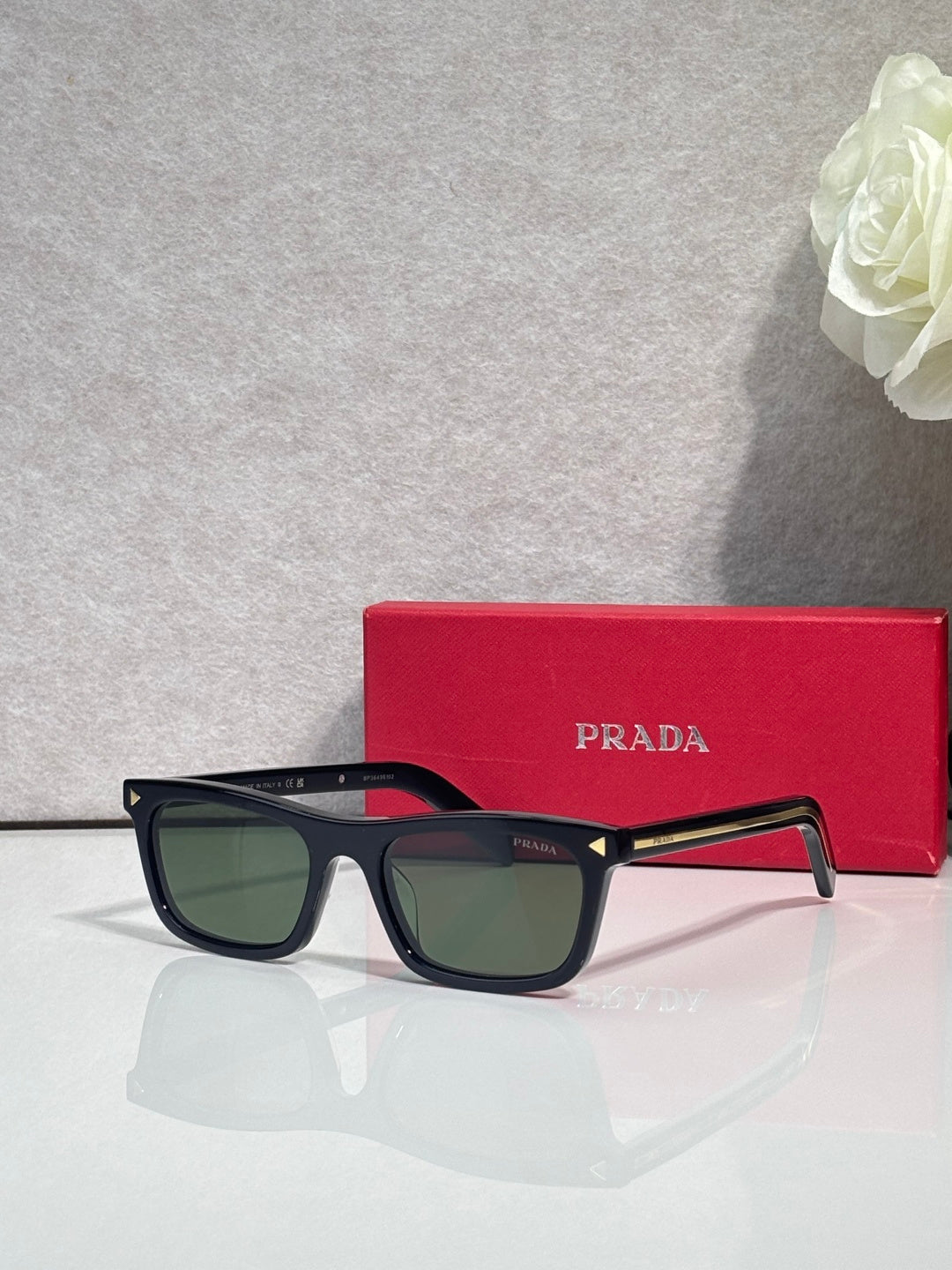 Prada sunglasses with black frame and green-tinted rectangular lenses