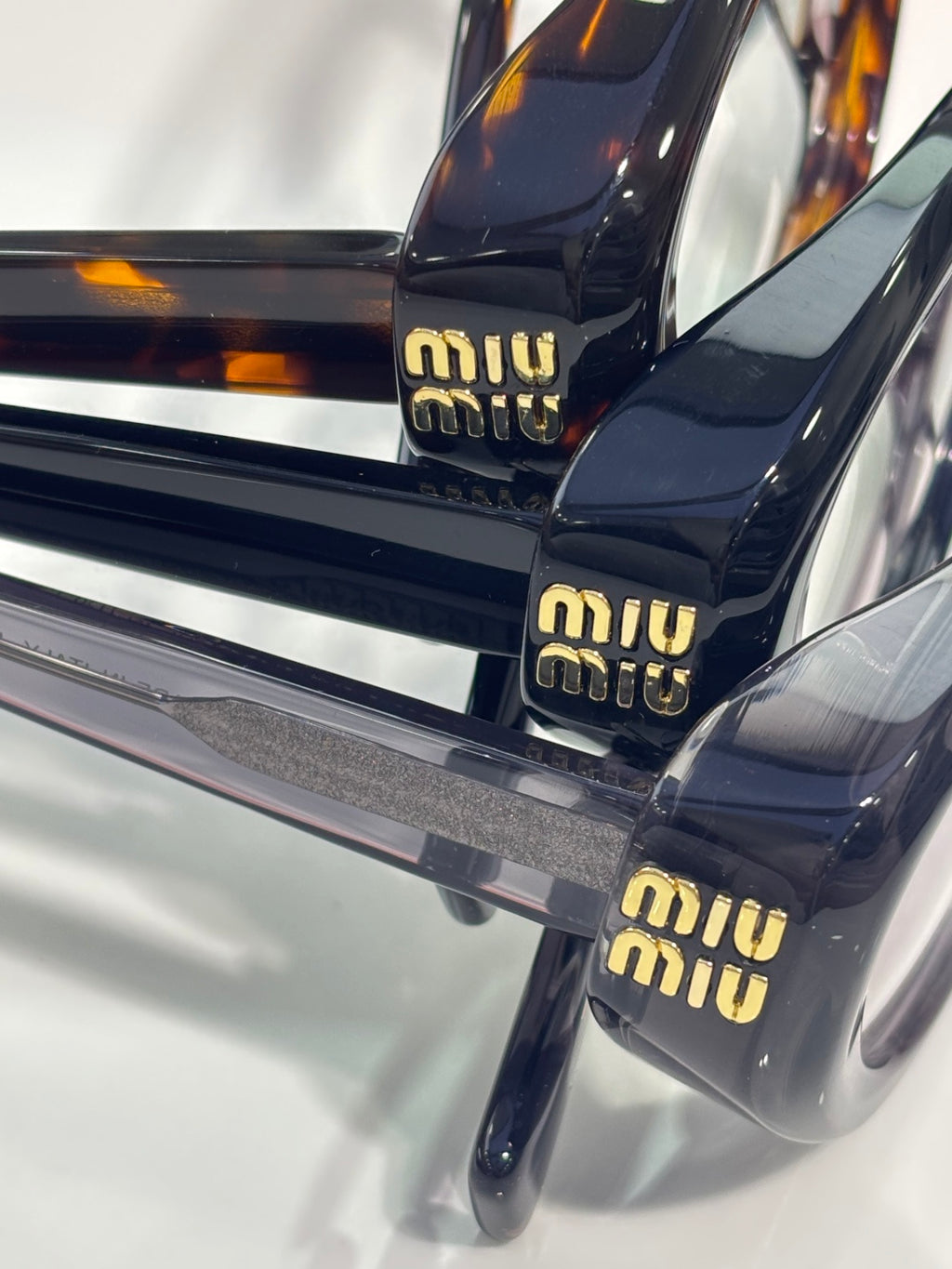 Miu Miu eyeglasses close-up: dark temples with gold “miu miu” lettering