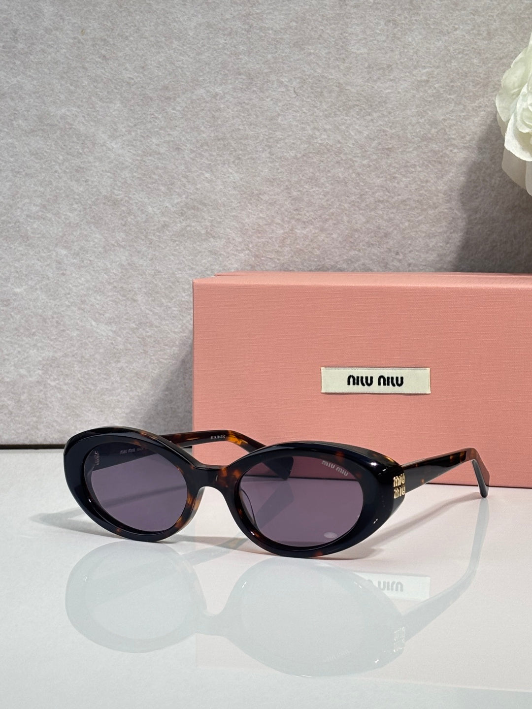 MiuMiu oval sunglasses with tortoise frames and purple-tinted lenses