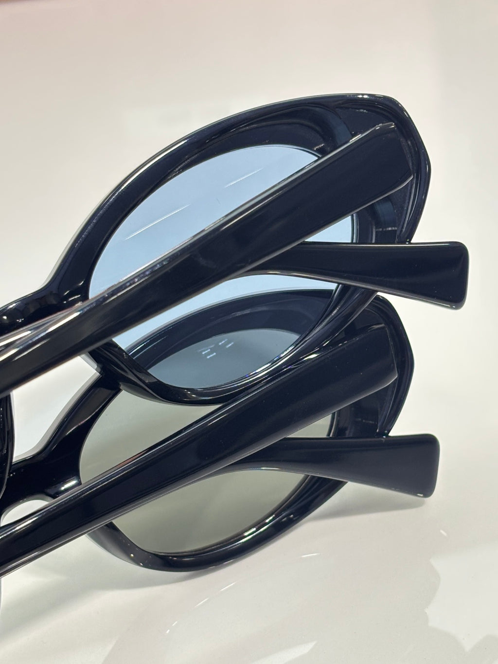 MiuMiu oval sunglasses close-up, glossy dark frames with curved temple arms