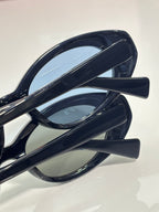 MiuMiu oval sunglasses close-up, glossy dark frames with curved temple arms