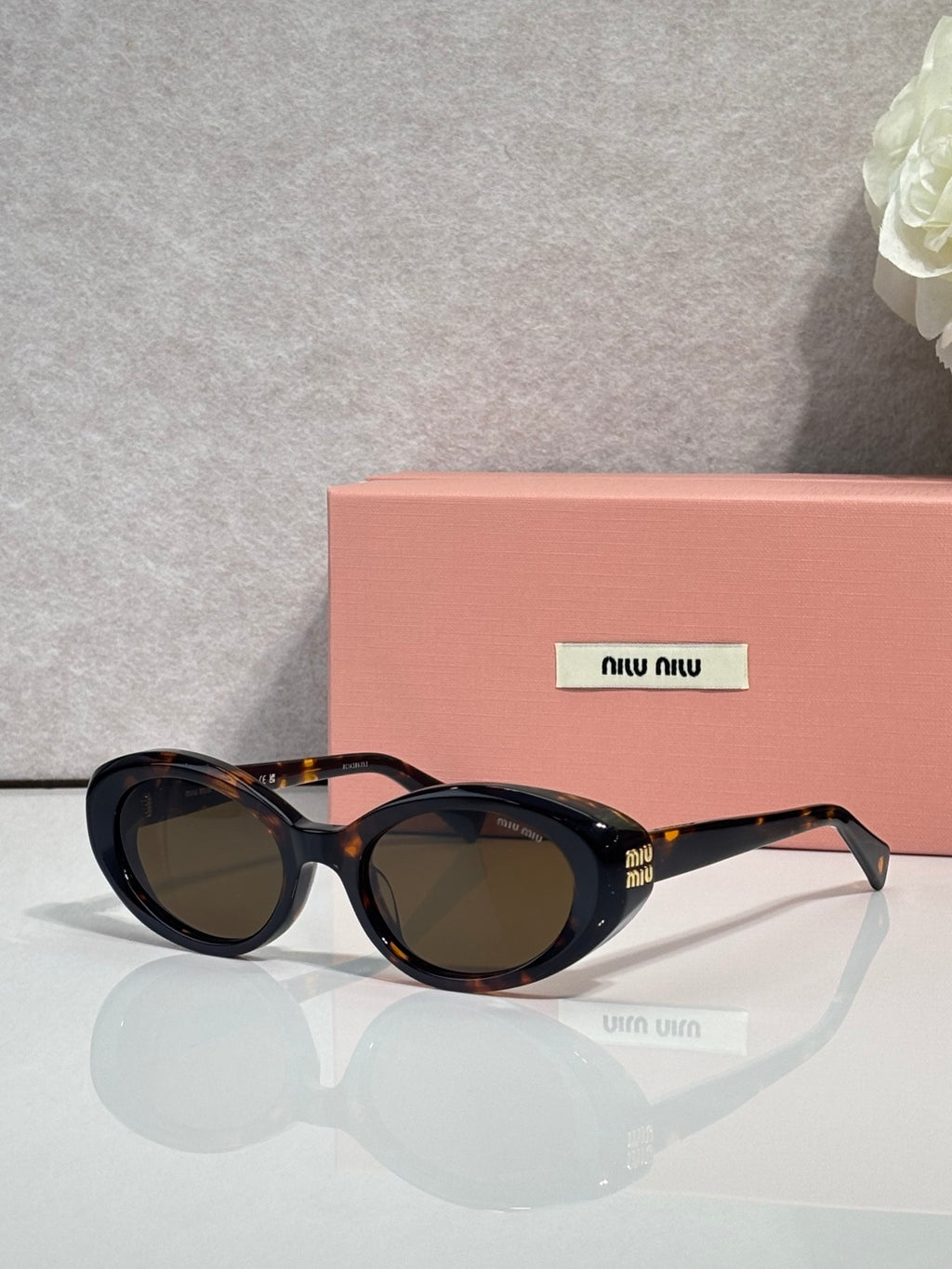 MiuMiu oval sunglasses with dark tortoise frames and dark tinted lenses