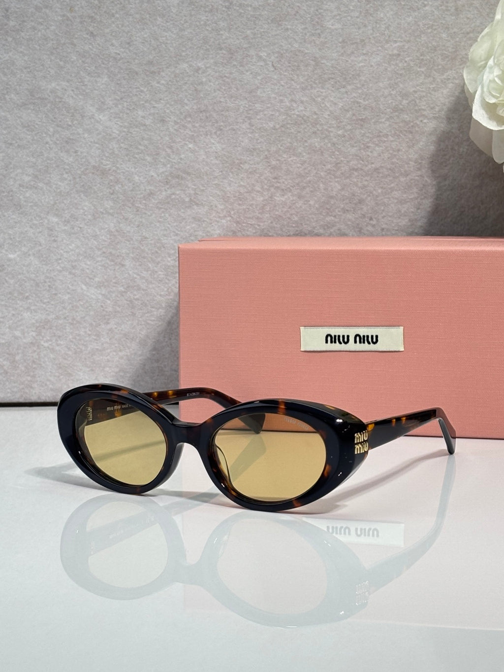 MiuMiu oval sunglasses with dark frames and amber-tinted lenses