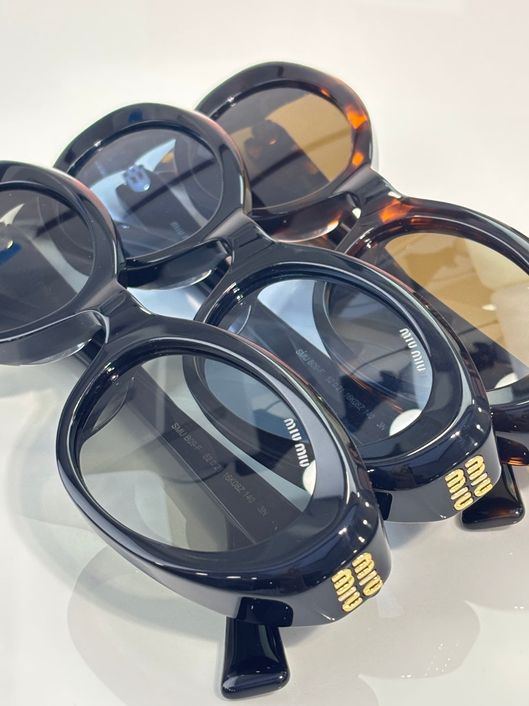 MiuMiu oval sunglasses set, dark frames with branded details and tinted lenses