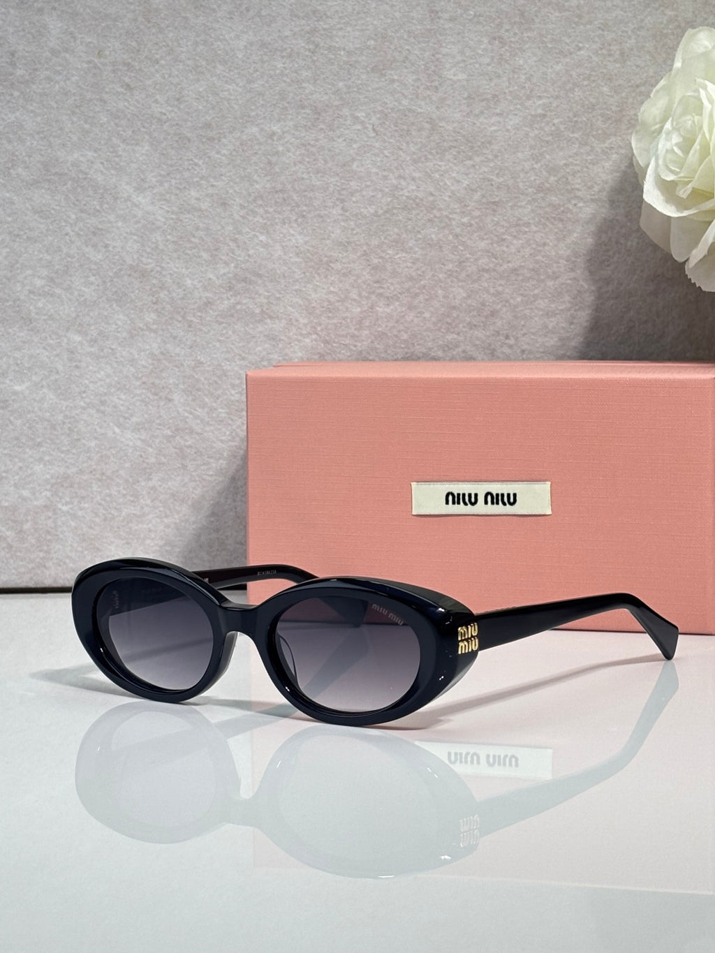 MiuMiu oval sunglasses with black frames and dark tinted lenses