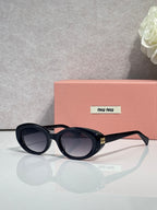 MiuMiu oval sunglasses with black frames and dark tinted lenses