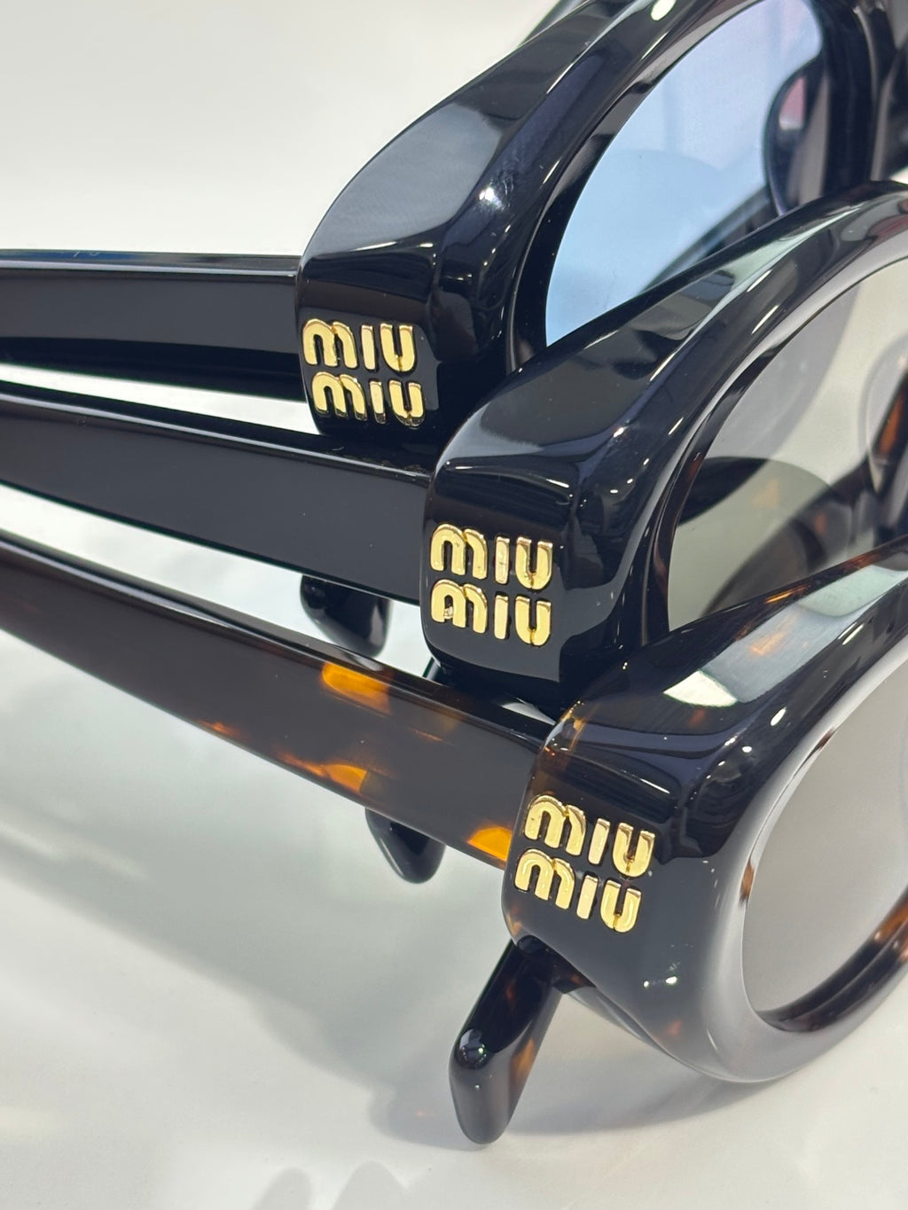 Miu Miu black sunglasses with tortoiseshell temple tips and Miu Miu logo text