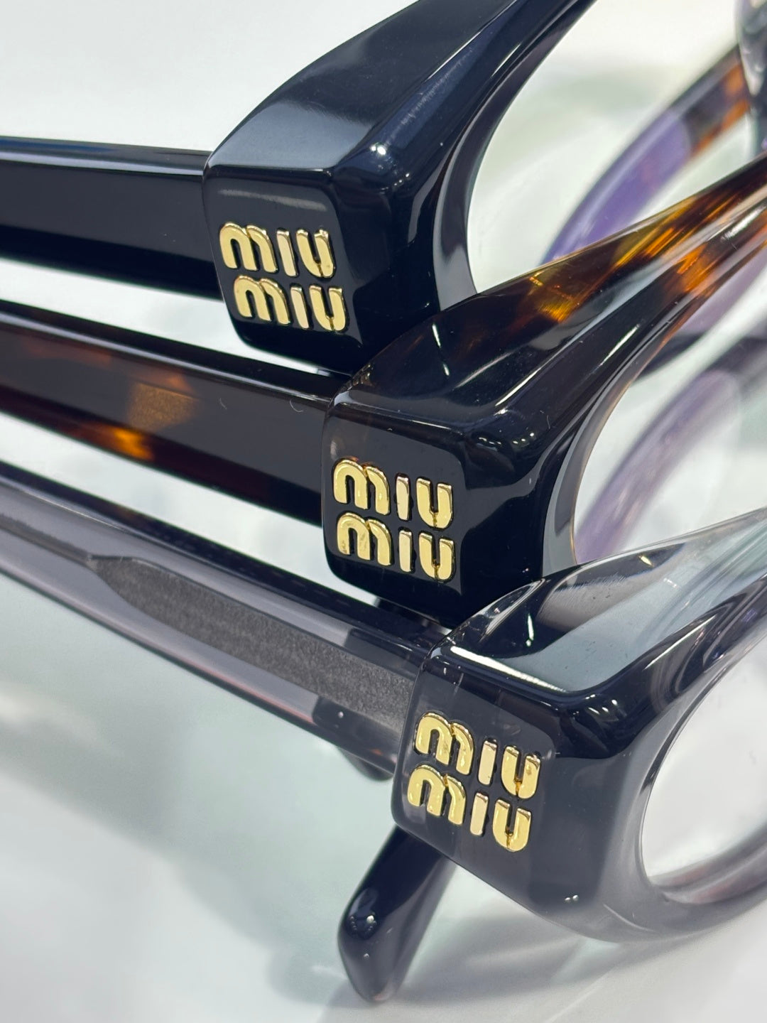 MiuMiu eyeglasses close-up of glossy black temples with gold logo print