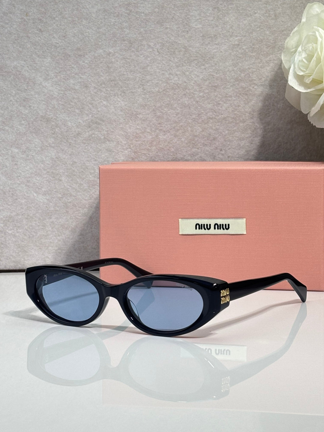 MiuMiu glasses with dark frames and blue-tinted oval lenses