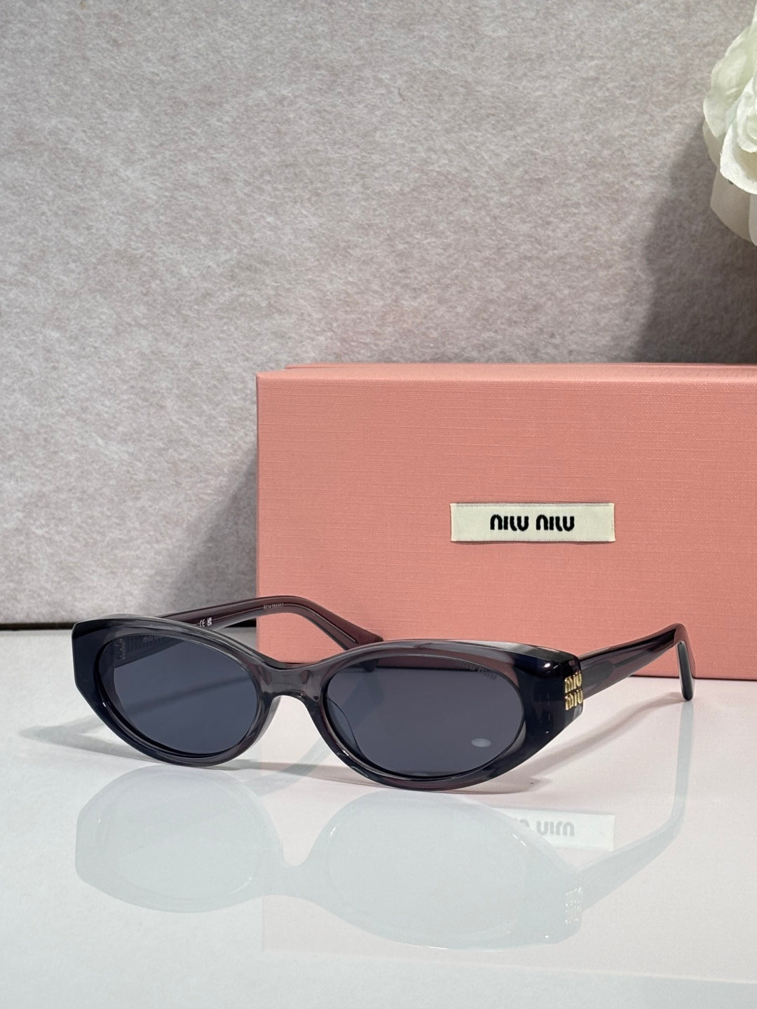 MiuMiu glasses with dark oval frames and dark tinted lenses