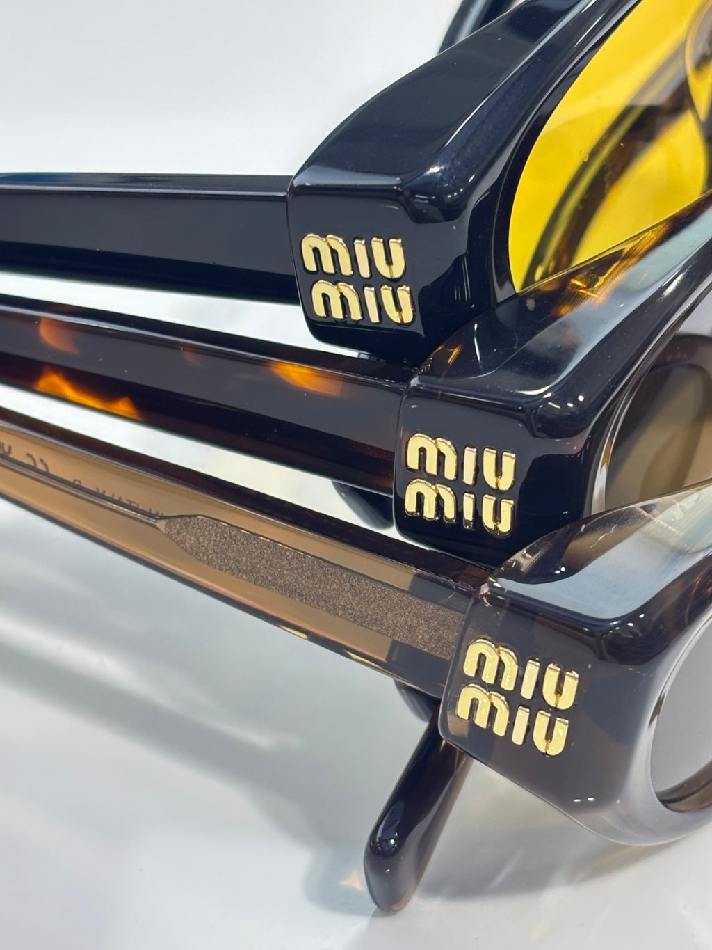MiuMiu glasses close-up with glossy dark frames and gold logo