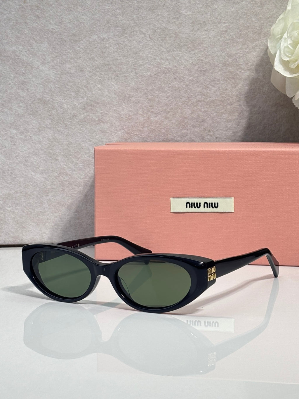Black cat-eye sunglasses with dark green lenses and gold logo detail