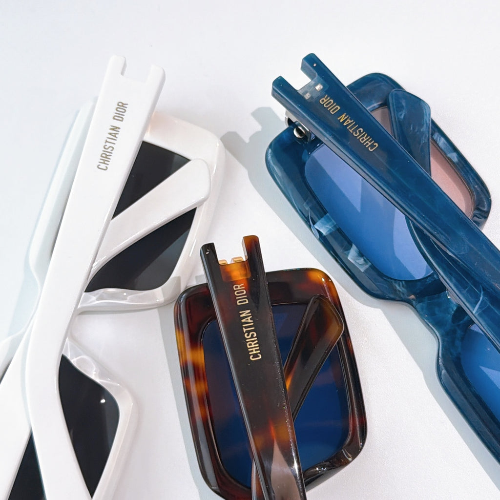 Dior sunglasses closeup, white and brown frames with gold hinges and branded temples