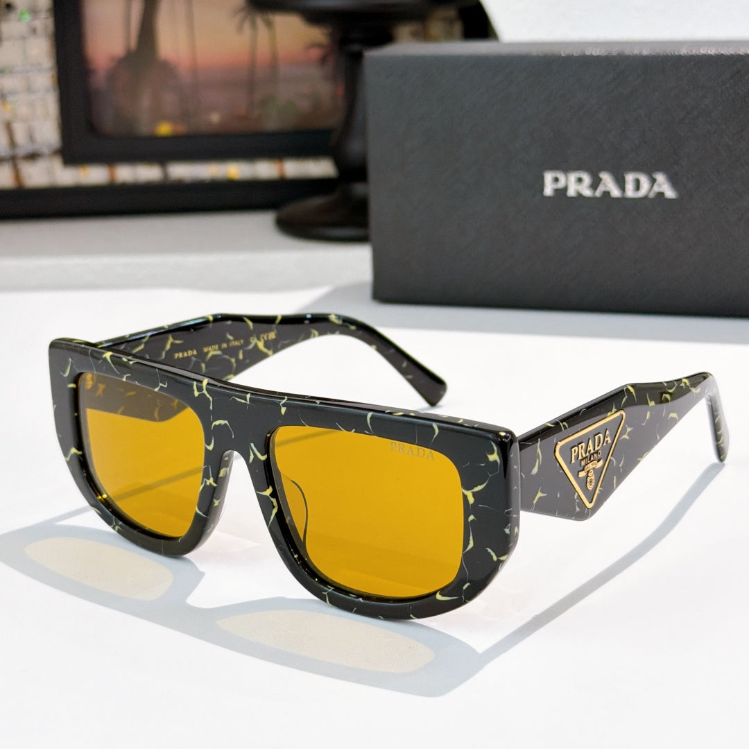 Prada sunglasses with black patterned frames and yellow tinted lenses, triangular logo detail.
