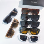 Assorted Prada sunglasses with dark, tortoiseshell, tan, and white frames; tinted lenses.