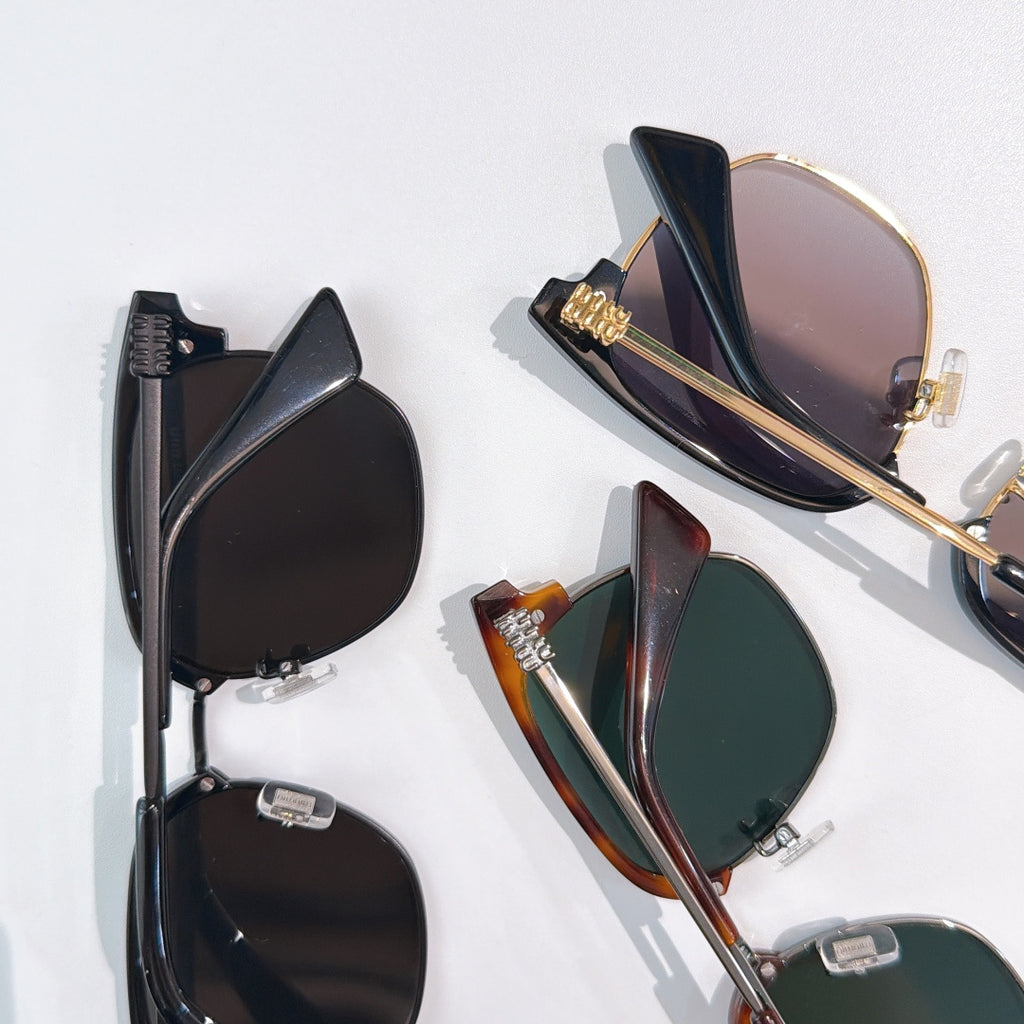 Sunglasses laid flat: black, tortoiseshell, and green-lens styles with metal hinges