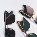 Sunglasses laid flat: black, tortoiseshell, and green-lens styles with metal hinges