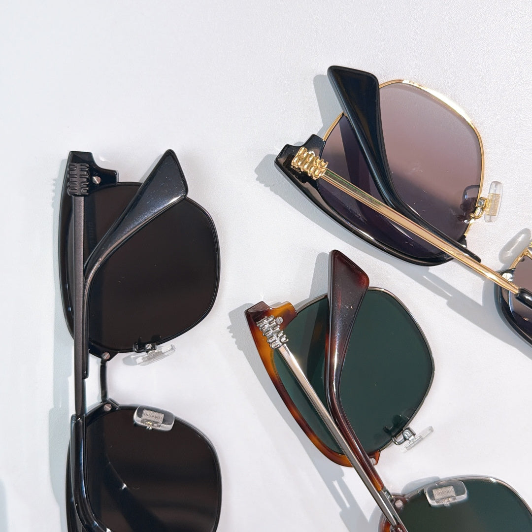 Sunglasses laid flat: black, tortoiseshell, and green-lens styles with metal hinges